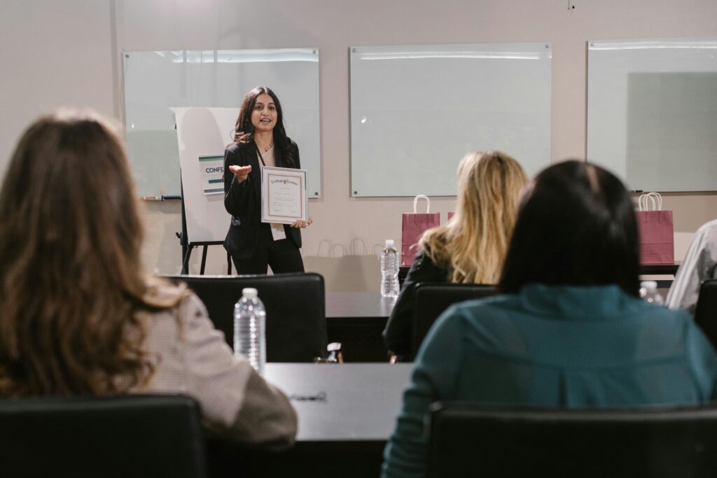 A business seminar showcasing a female presenter awarding certificates to attendees.